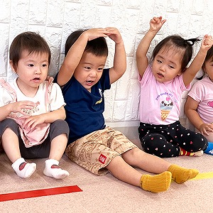 英語レッスンで両手を上げたり大きく丸を作る子どもたち